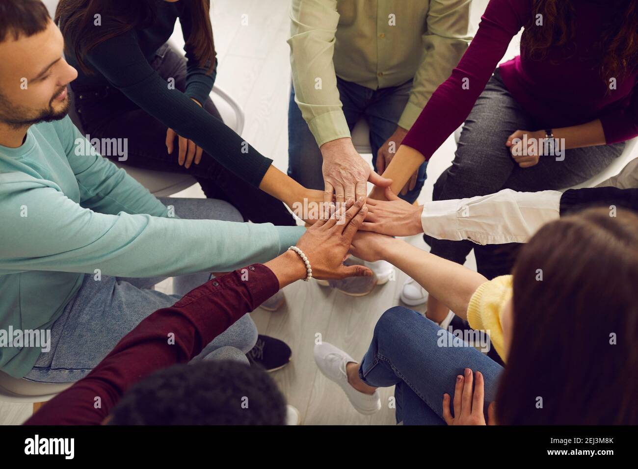 Alto angolo di persone che si uniscono mani in riunione di comunità o. sessione di terapia di gruppo Foto Stock