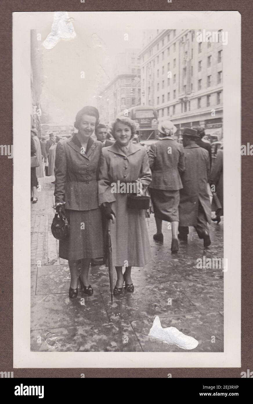 Foto in bianco e nero d'epoca di due donne che osservano molto astuto nei cappotti invernali nella trafficata strada degli anni '30. Foto Stock