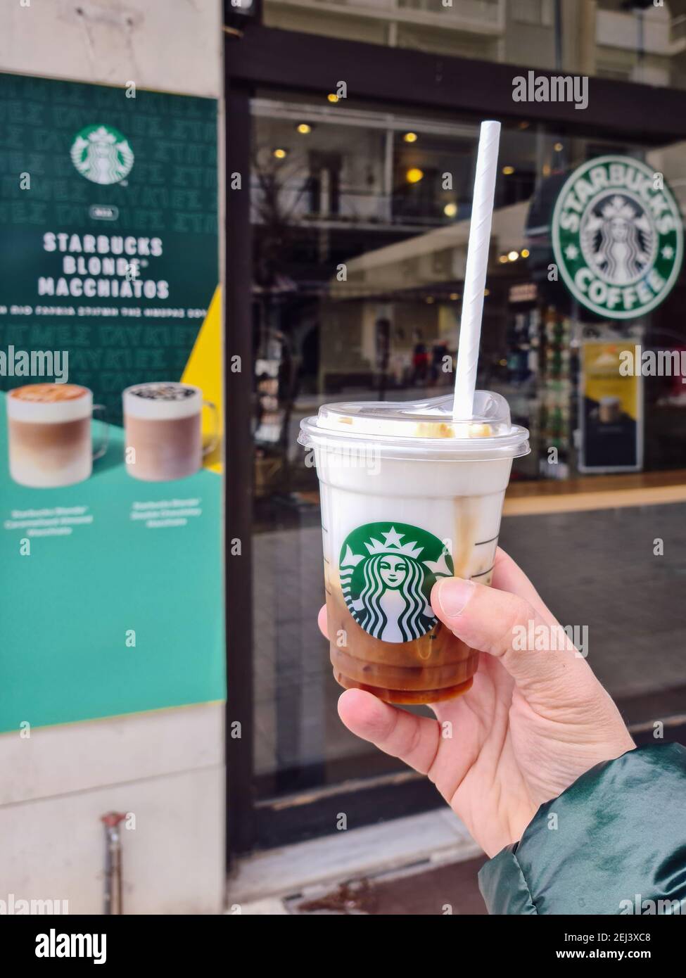Salonicco, Grecia – Febbraio 20 2021: Tazza da caffè da asporto Starbucks  Cloud Macchiato con coperchio senza cannuccia. Tenere a mano all'esterno  del negozio una bevanda fredda di marca con il logo