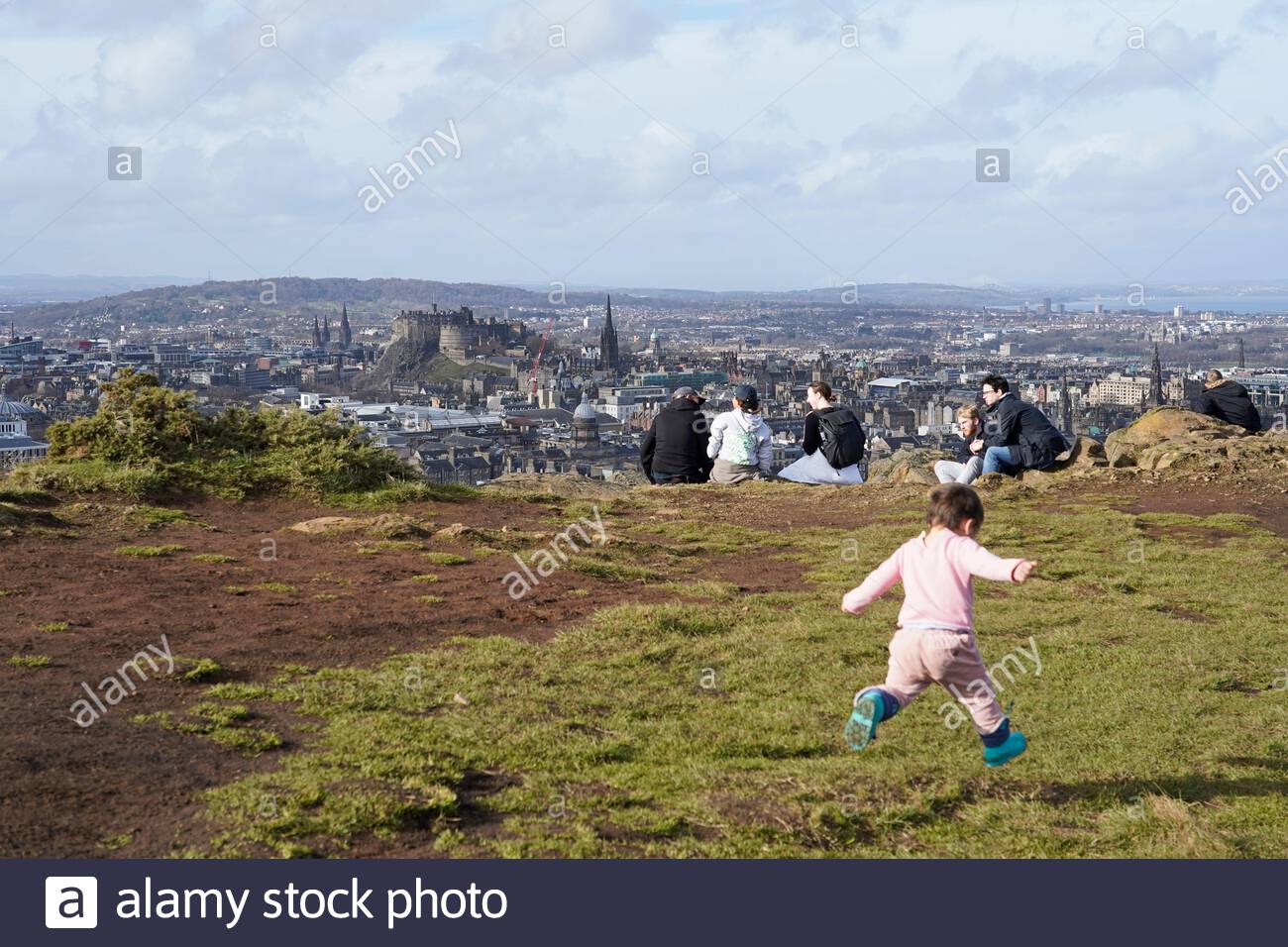 Edimburgo, Scozia, Regno Unito. 21 Feb 2021. Le persone che si godono il sole e all'aperto in Holyrood Park. Da Salisbury Crags si può ammirare il Castello di Edimburgo e i tetti del centro della città. Credit: Craig Brown/Alamy Live News Foto Stock