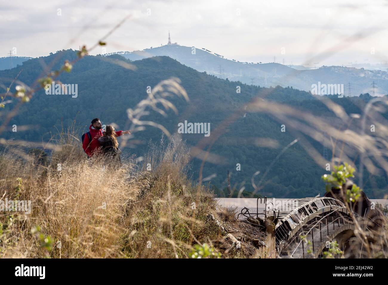 DOS senderistas miran la extension del Parque del Collserola arriba de una antigua fabrica abandonada, un raro testimonio de arcqueologia industrial d Foto Stock