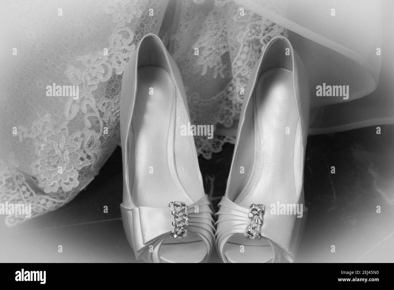 Una vista in scala di grigi closeup di scarpe da sposa bianche e il veli della sposa Foto Stock