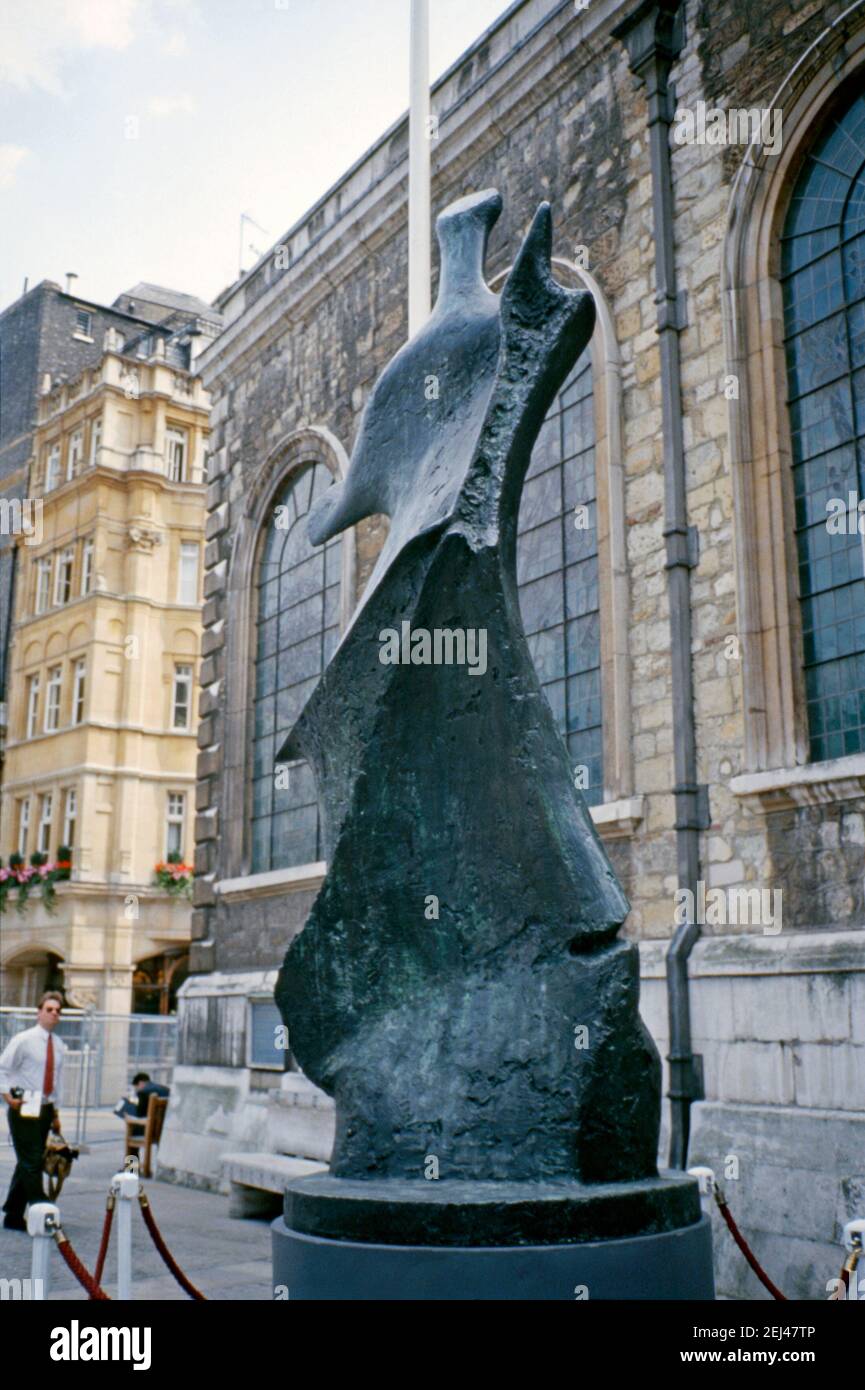 Una scultura in bronzo del 1976, il ‘STanding Figure: Knut Edge’ di Henry Moore, esposta fuori dalla chiesa della Gioielleria di San Lorenzo, Guildhall Yard, City of London, England, UK 1993. Questo faceva parte della ‘Arte nella Città’ del 1993 e mirava a mettere la scultura tra gli spazi verdi e la caratteristica architettura della Città di Londra. ‘STanding Figure: Knife Edge’ è una scultura in bronzo di Henry Moore. È stato fuso in due versioni, ‘STanding Figure: Knife Edge’ (1961), e come mostrato qui, un ‘Large Standing Figure: Knife Edge’ (1976). È stato esposto in molte località in tutto il mondo. Foto Stock
