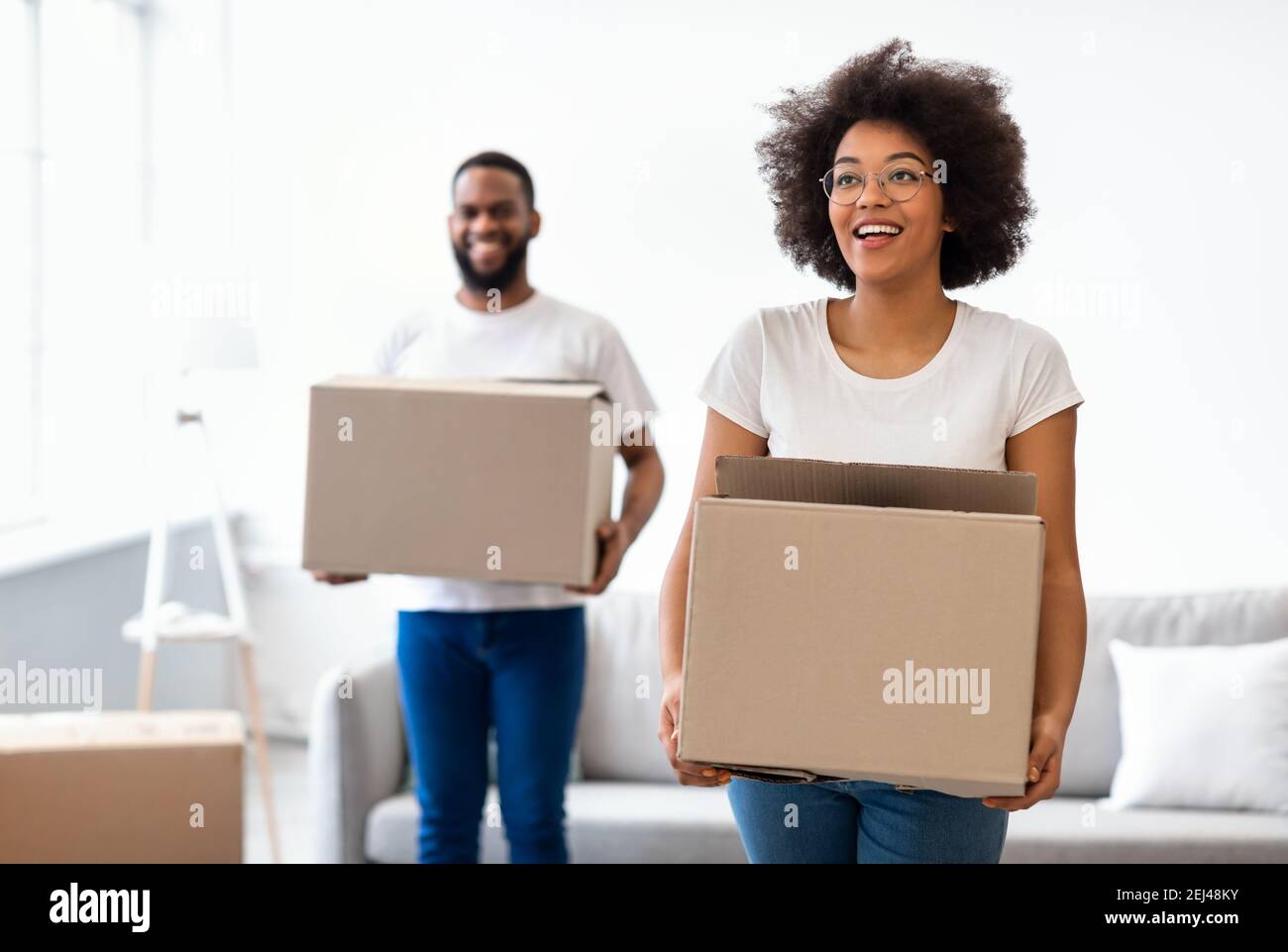 I coniugi gioiosi neri trasportano le scatole mobili che entrano insieme nella nuova casa Foto Stock