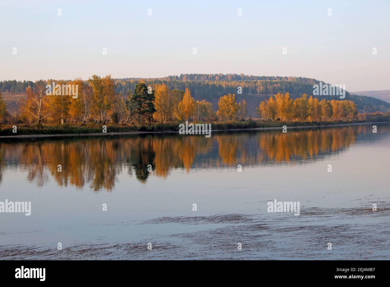 Vista sulla tranquilla superficie del fiume, dove si riflette il paesaggio autunnale, come in un grande specchio. Foto Stock