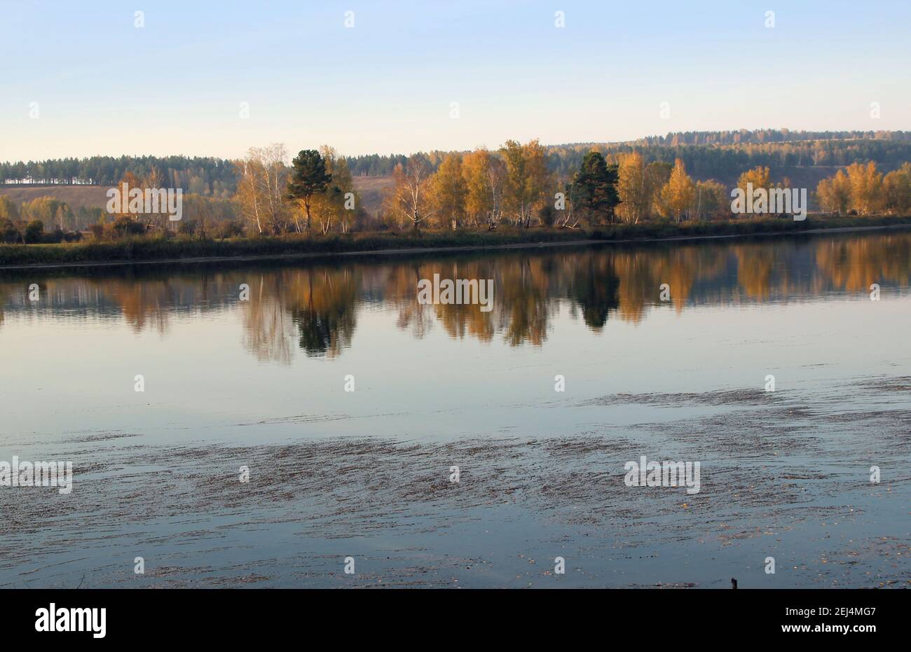 Vista sulla tranquilla superficie del fiume, dove si riflette il paesaggio autunnale, come in un grande specchio. Foto Stock