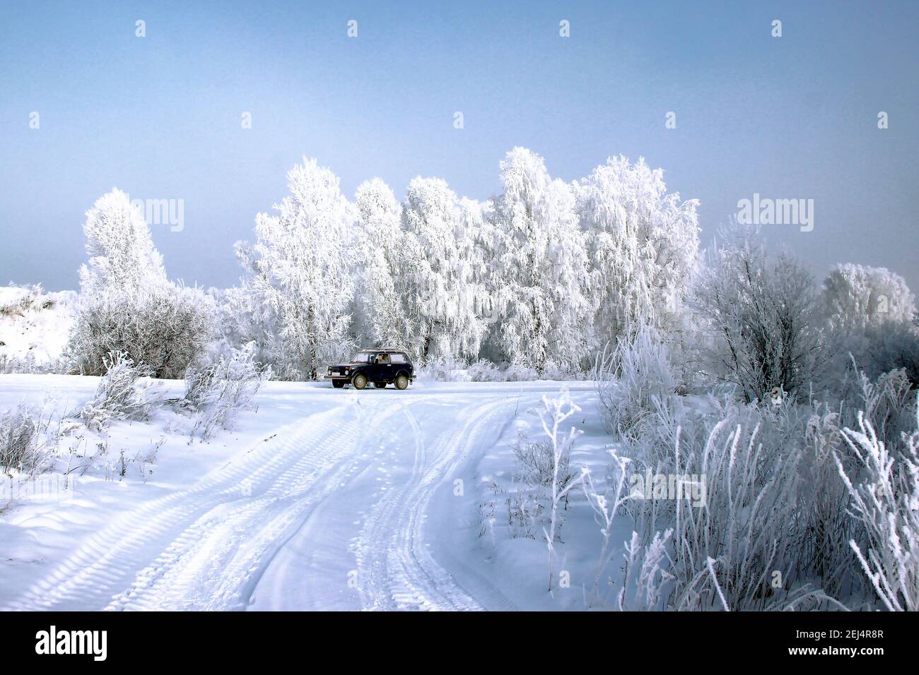 Una giornata invernale limpida. Cielo blu chiaro e gelido. Un'auto sola a un bivio in strada. Foto Stock