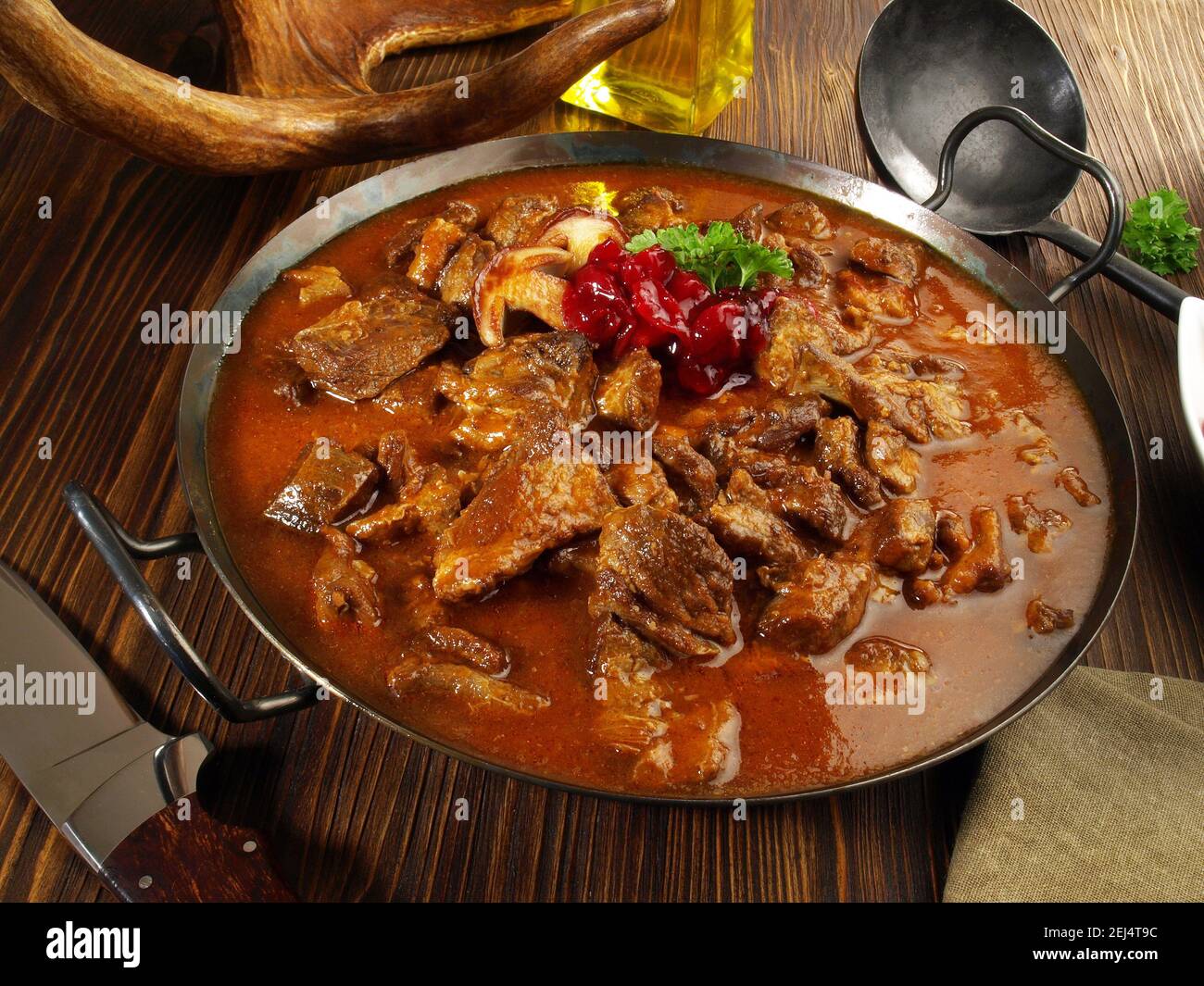 Selvaggina goulash di carne in una padella con mirtilli rossi su Legno di fondo Foto Stock Selvaggina goulash di carne in una padella con mirtilli rossi su Legno di fondo Foto Stock