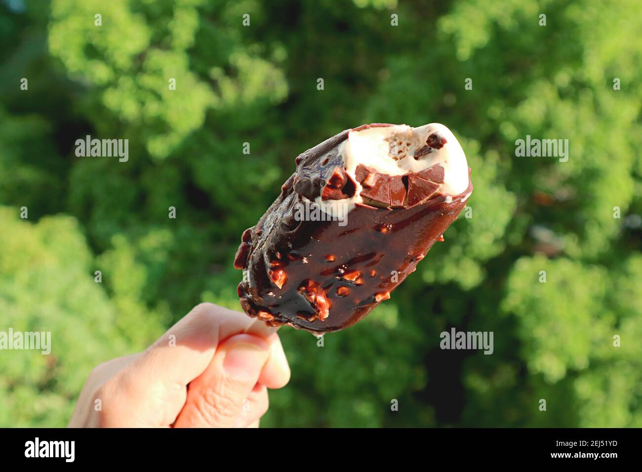 Closeup una fusione cioccolato immerso Ice Cream Bar in mano In un giorno di sole Foto Stock