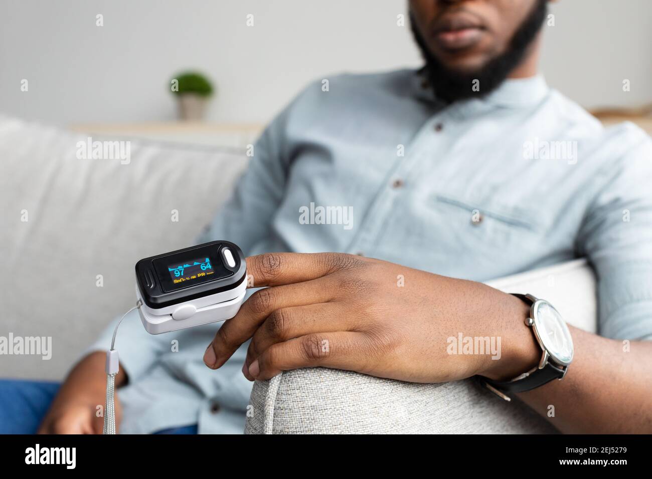 Black Man con pulsossimetro che misura la saturazione dell'ossigeno a casa  Foto stock - Alamy