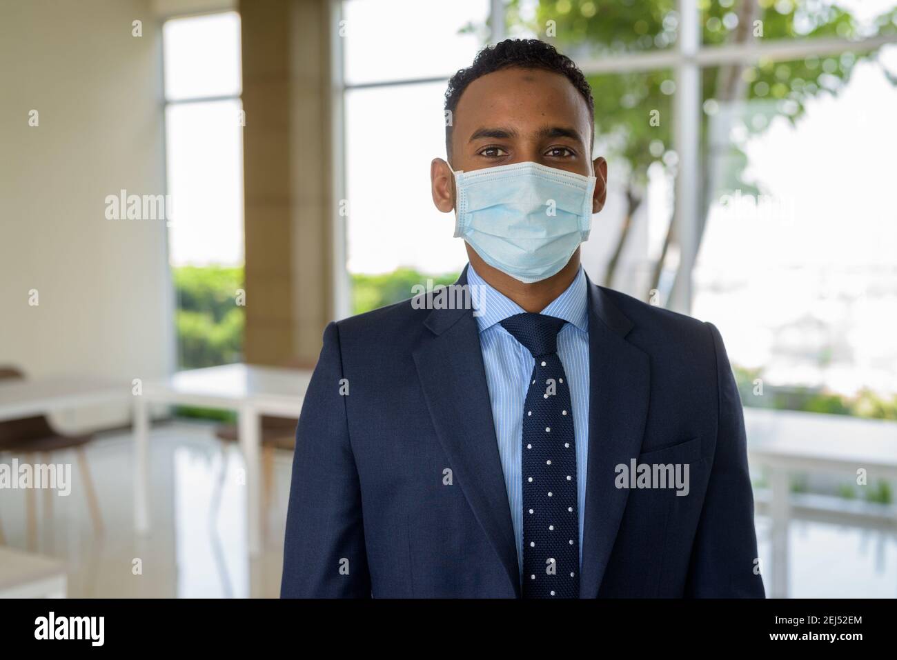 Uomo d'affari africano con maschera medica chirurgica per la protezione in ufficio Foto Stock