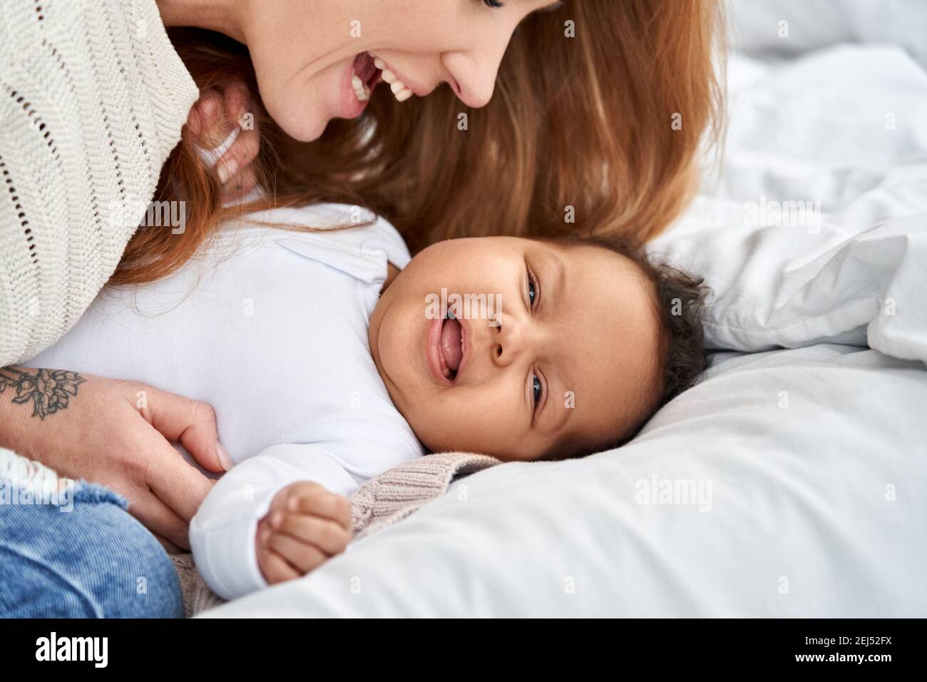 Buona madre caucasica che si diverte con la bambina carina sul letto. Foto Stock