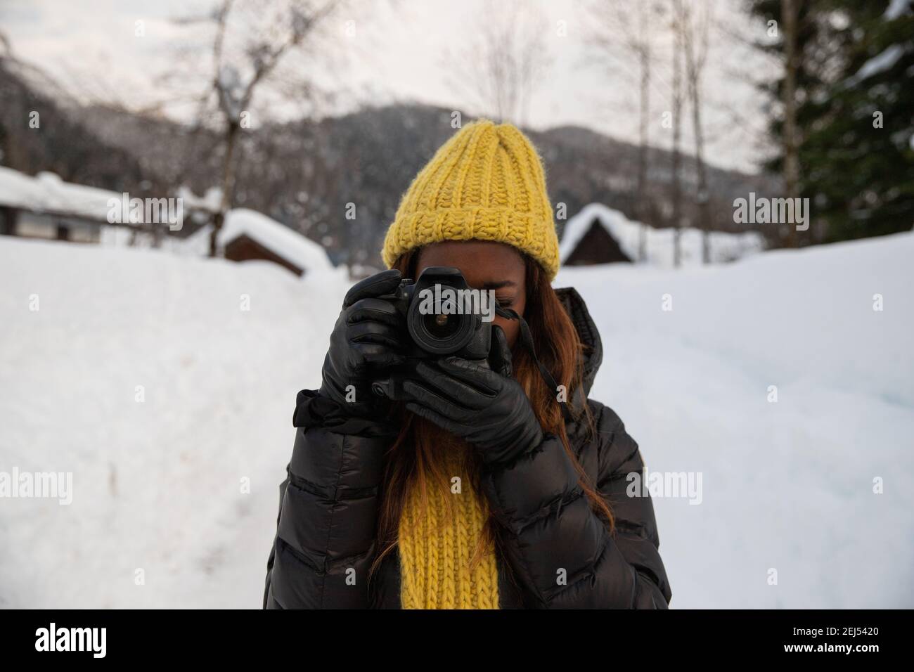 Un fotografo scatta una foto mentre si è in piedi in montagna scenario nel freddo con la neve Foto Stock