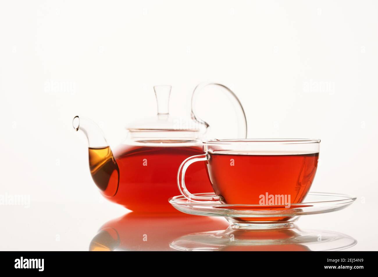Tazza in vetro di tè aromatico caldo e teiera su bianco sfondo Foto Stock