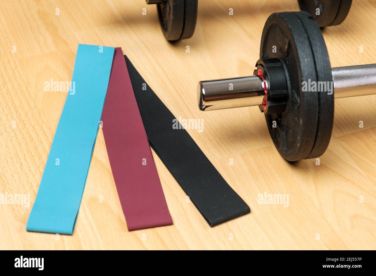 Manubri e fasce elastiche sul pavimento a casa. Mantenersi in forma durante il blocco. Attrezzature fitness per l'allenamento di forza Foto Stock Manubri e fasce elastiche sul pavimento a casa. Mantenersi in forma durante il blocco. Attrezzature fitness per l'allenamento di forza Foto Stock