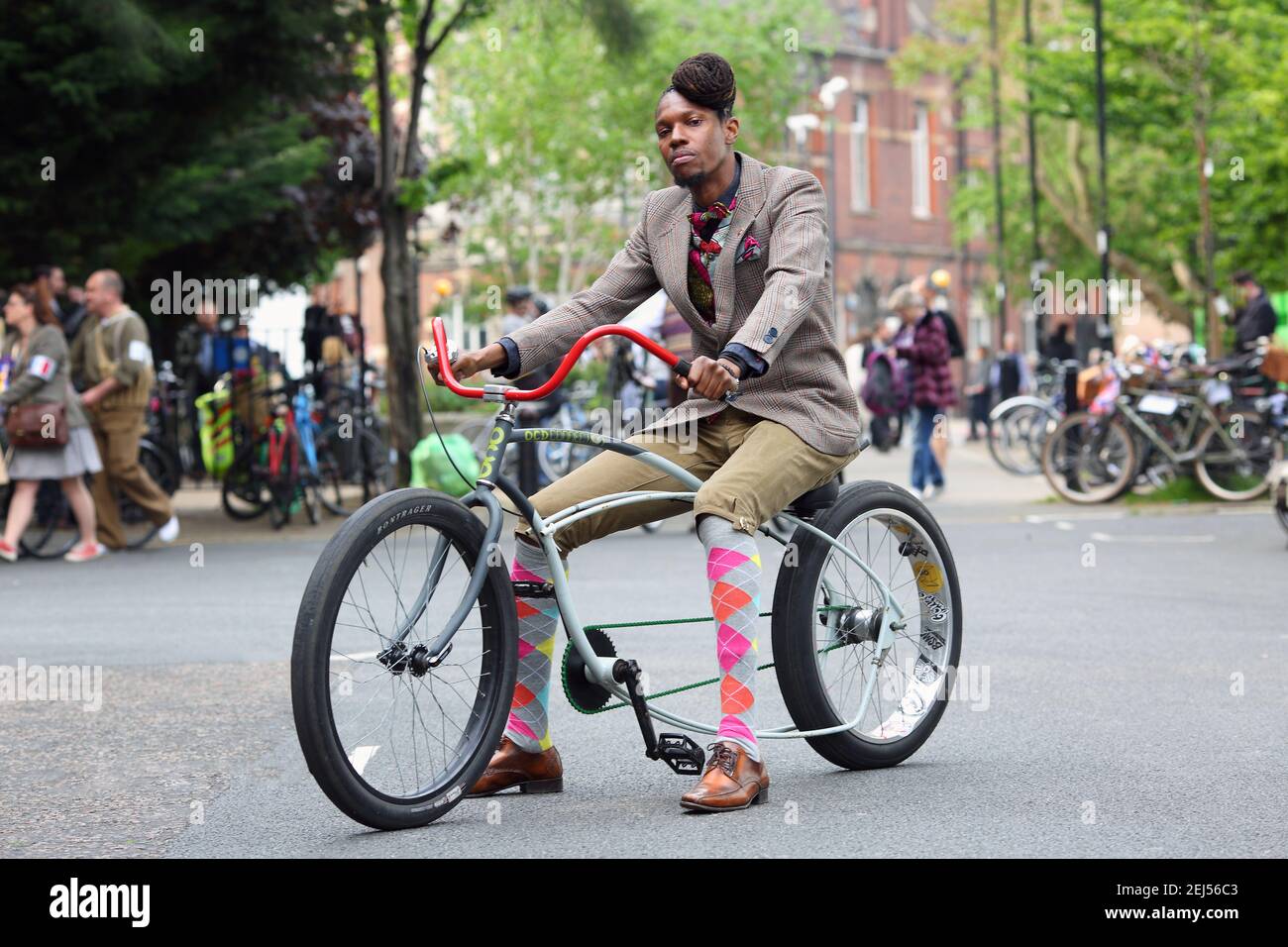 Uomo britannico afro-caraibico vestito in tweed seduto sulla bicicletta di abitudine del lowrider a Londra, Regno Unito Foto Stock