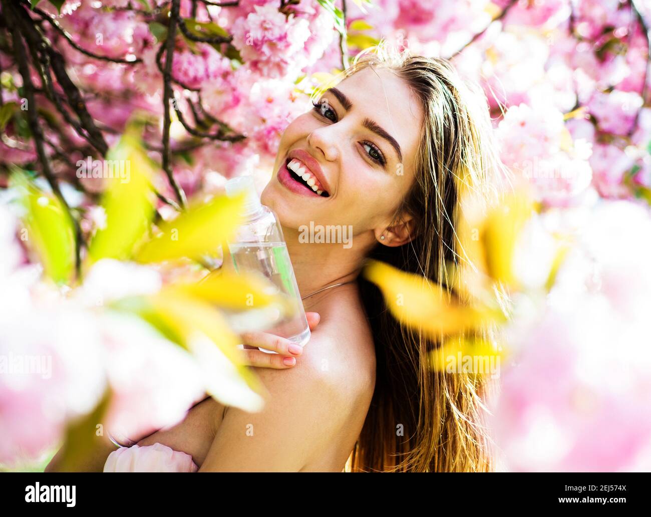 Donna con bottiglia di acqua detergente. Rimuovi trucco. Acqua micellare. Cosmetici. Cosmetologia. Cura della pelle. Trattamento di bellezza. Tonico facciale. Bellezza della natura. Foto Stock