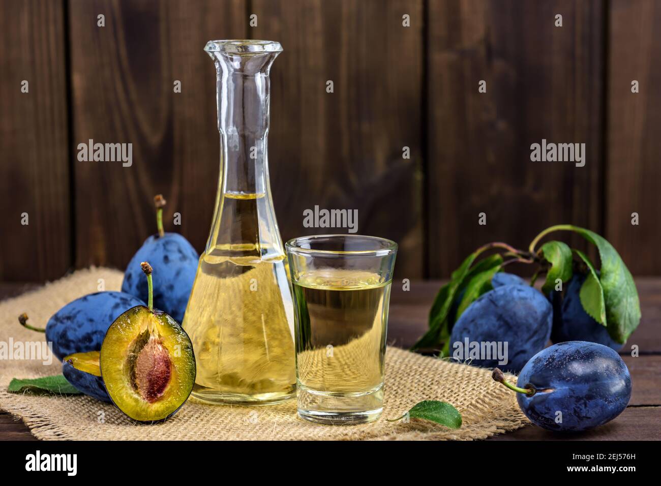 Brandy di prugne o schnapps in bicchieri e prugne fresche gustose su un tavolo di legno. Messa a fuoco selettiva. Foto Stock