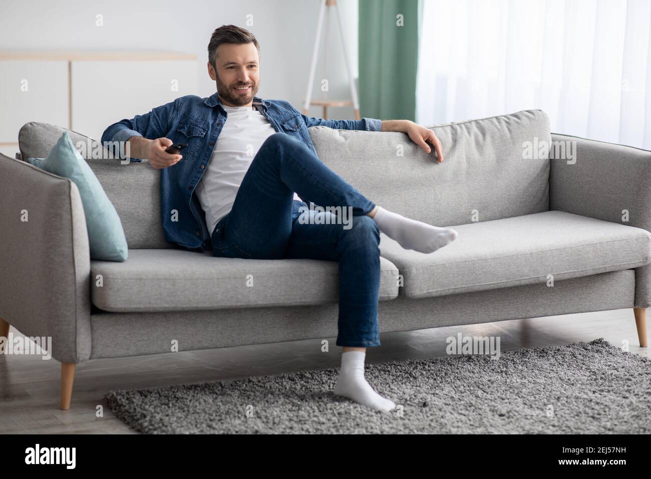 Uomo rilassato guardando la TV a casa, spazio per la copia Foto Stock