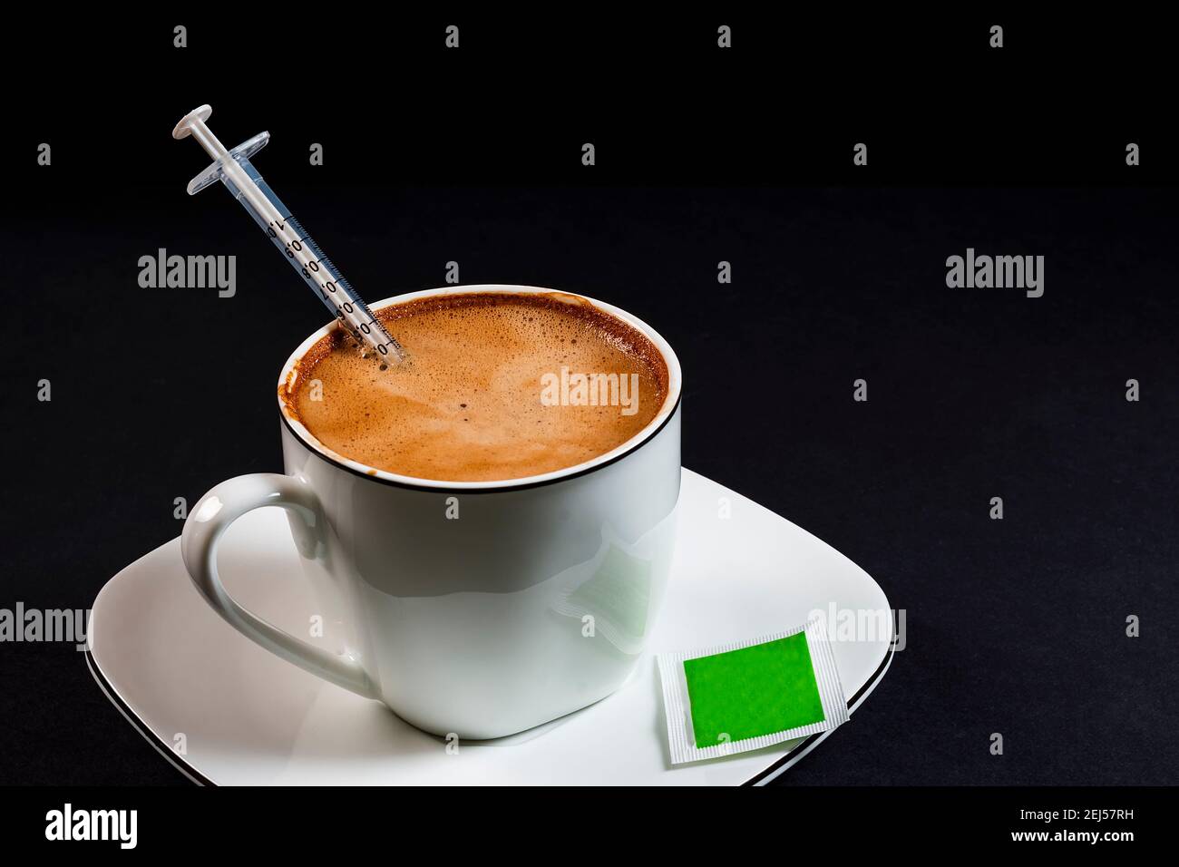 Caffè con latte in tazza di porcellana con siringa all'interno del Coffee.questa è una foto in formato orizzontale scattata contro un nero sfondo sotto artificiale l Foto Stock