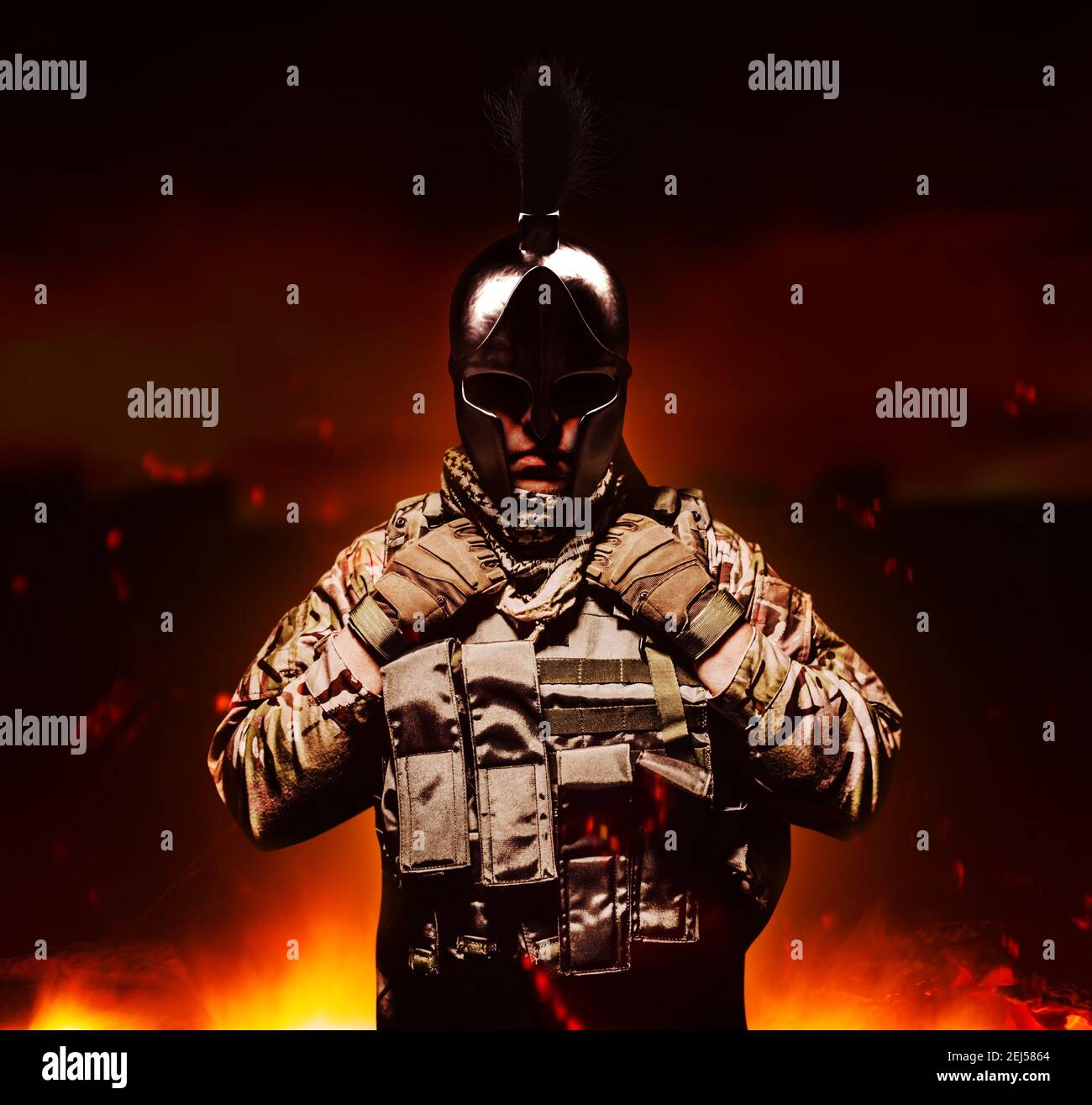 Soldato in gilet corazzato e munizioni in piedi su terra bruciante sfondo in antico casco spartano. Foto Stock