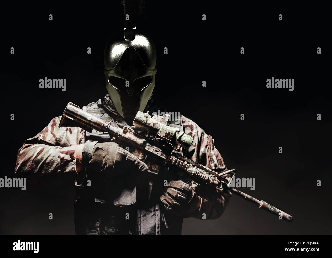 Soldato in gilet corazzato e munizioni in piedi su sfondo balcato in antico casco spartano con fucile automatico. Foto Stock