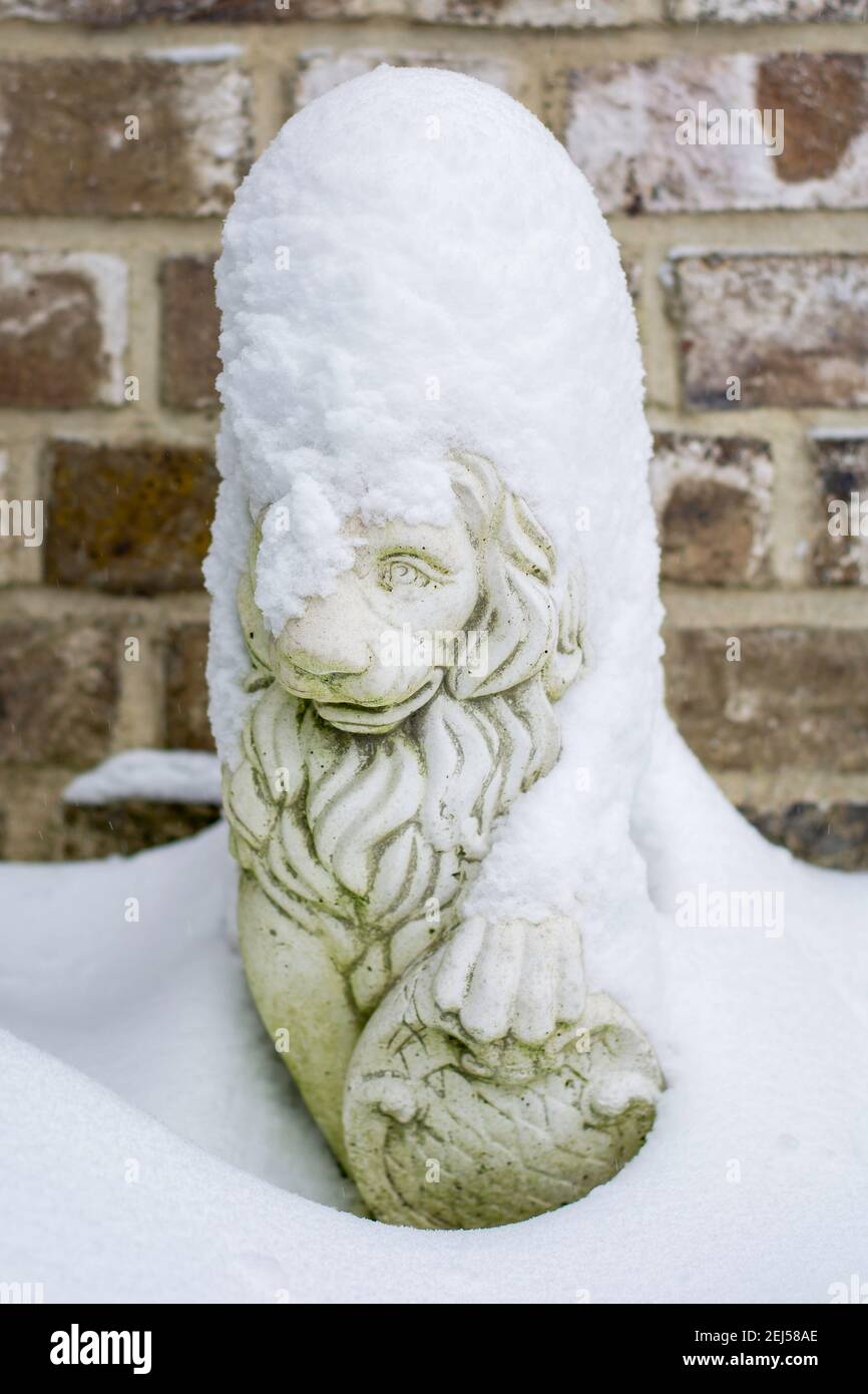 Scultura di un leone coperto di neve durante una fredda giornata invernale. Piccola statua coperta di neve fresca Foto Stock