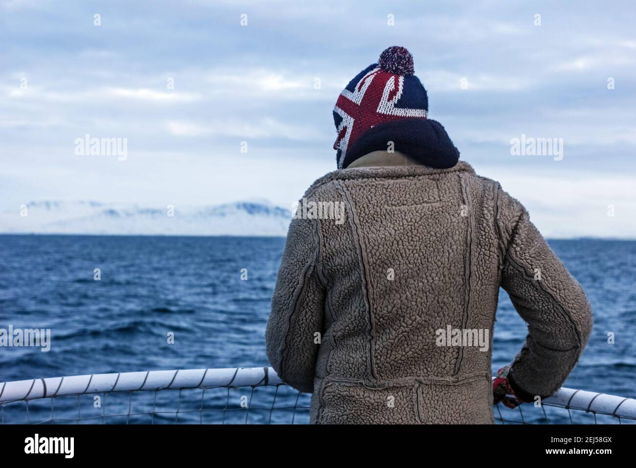 Gennaio, 3, 2016 - nave dell'oceano Atlantico, Islanda; l'uomo reale guarda in lontananza alle montagne innevate e al mare freddo Foto Stock