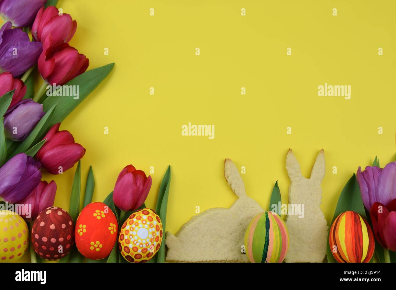 tulipani, uova dipinte e biscotti a forma di pulcino su sfondo giallo Foto Stock