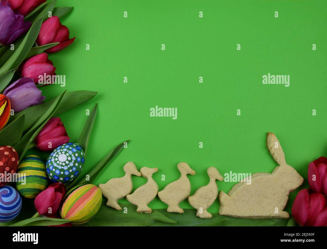 tulipani, uova dipinte e biscotti a forma di coniglietto e pulcino su sfondo verde Foto Stock