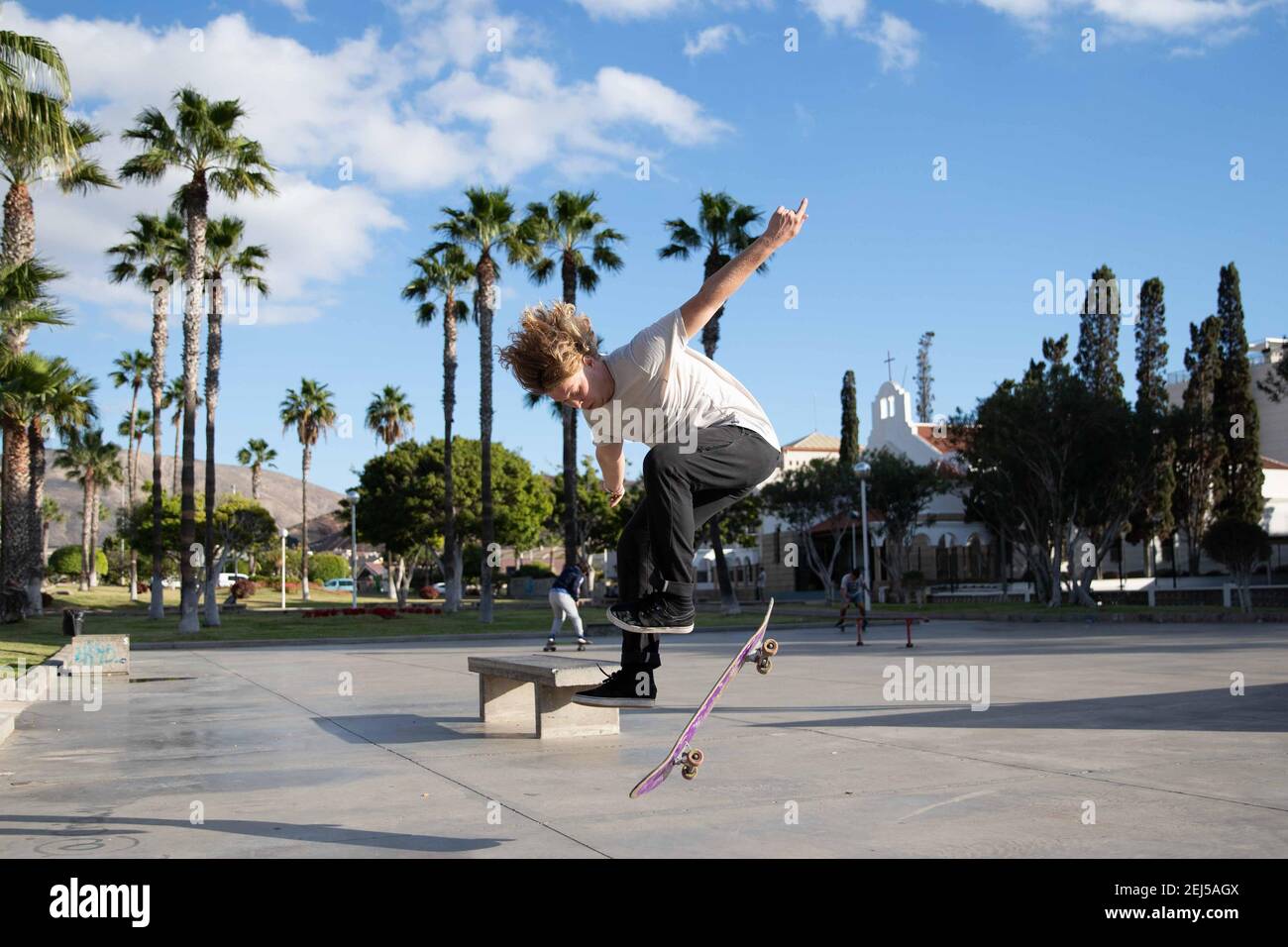 Lo skater esegue un kickflip mentre cavalca il suo skateboard skatepark Foto Stock