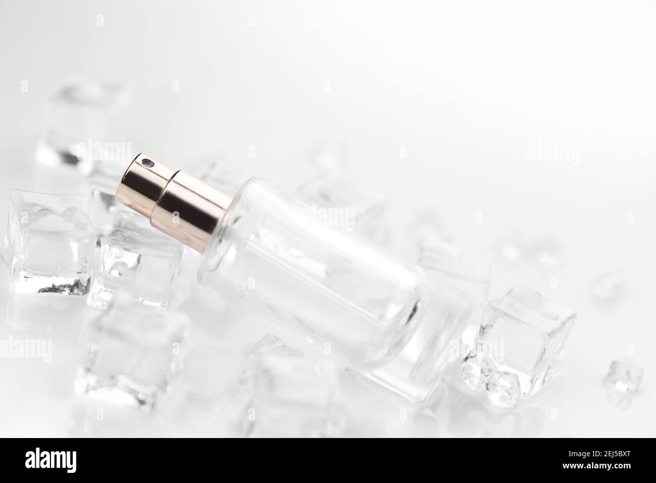 Bottiglia di profumo femminile, fotografia obiettiva di bottiglia di profumo in cubetti di ghiaccio e acqua. Vista dall'alto. Foto prodotto, concetto di freschezza e aroma Foto Stock