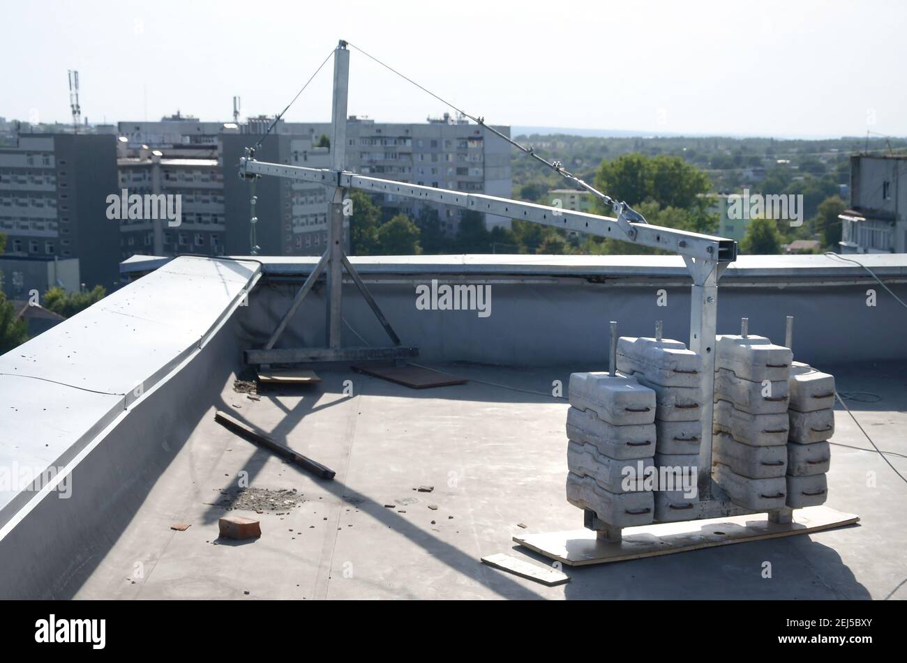 Contrappeso o bilanciamento del peso blocchi di calcestruzzo o mattoni come parte di una piattaforma di funi sospese per lavori di facciata su edifici ad alto livello multipiano. Uomo Foto Stock