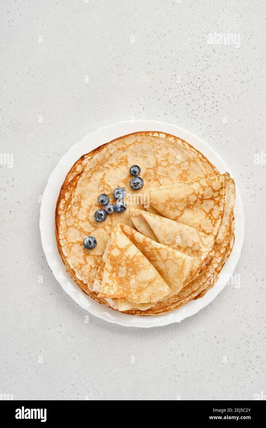 Frittelle sottili, crepes o blini con frutti di bosco in piatto bianco. Vista dall'alto. Settimana della frittella. Shrovetide. Spazio per il testo. Foto Stock