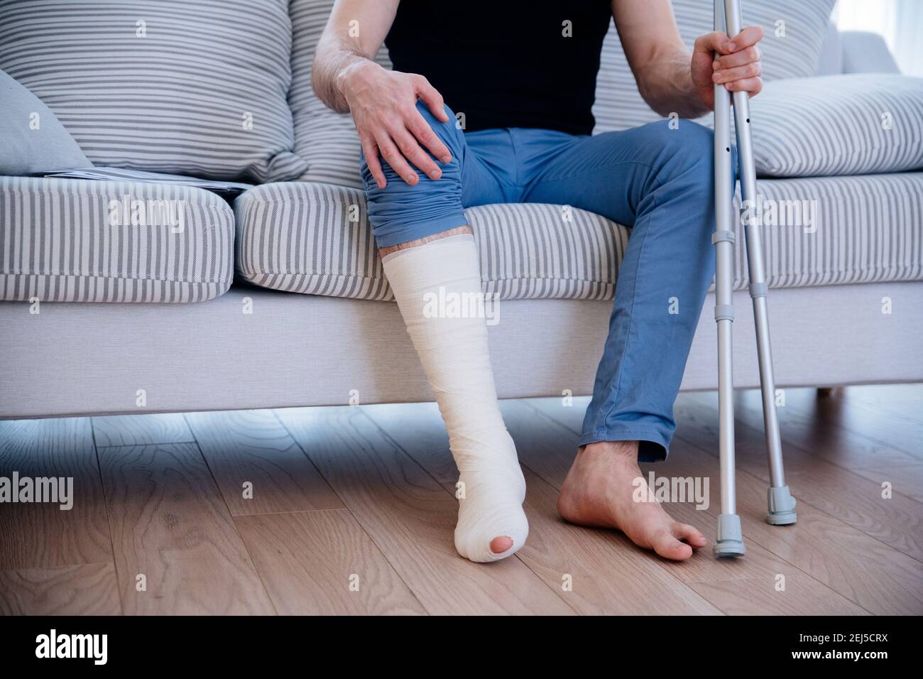 Uomo con gamba rotta a casa. Gamba in gesso Foto stock - Alamy
