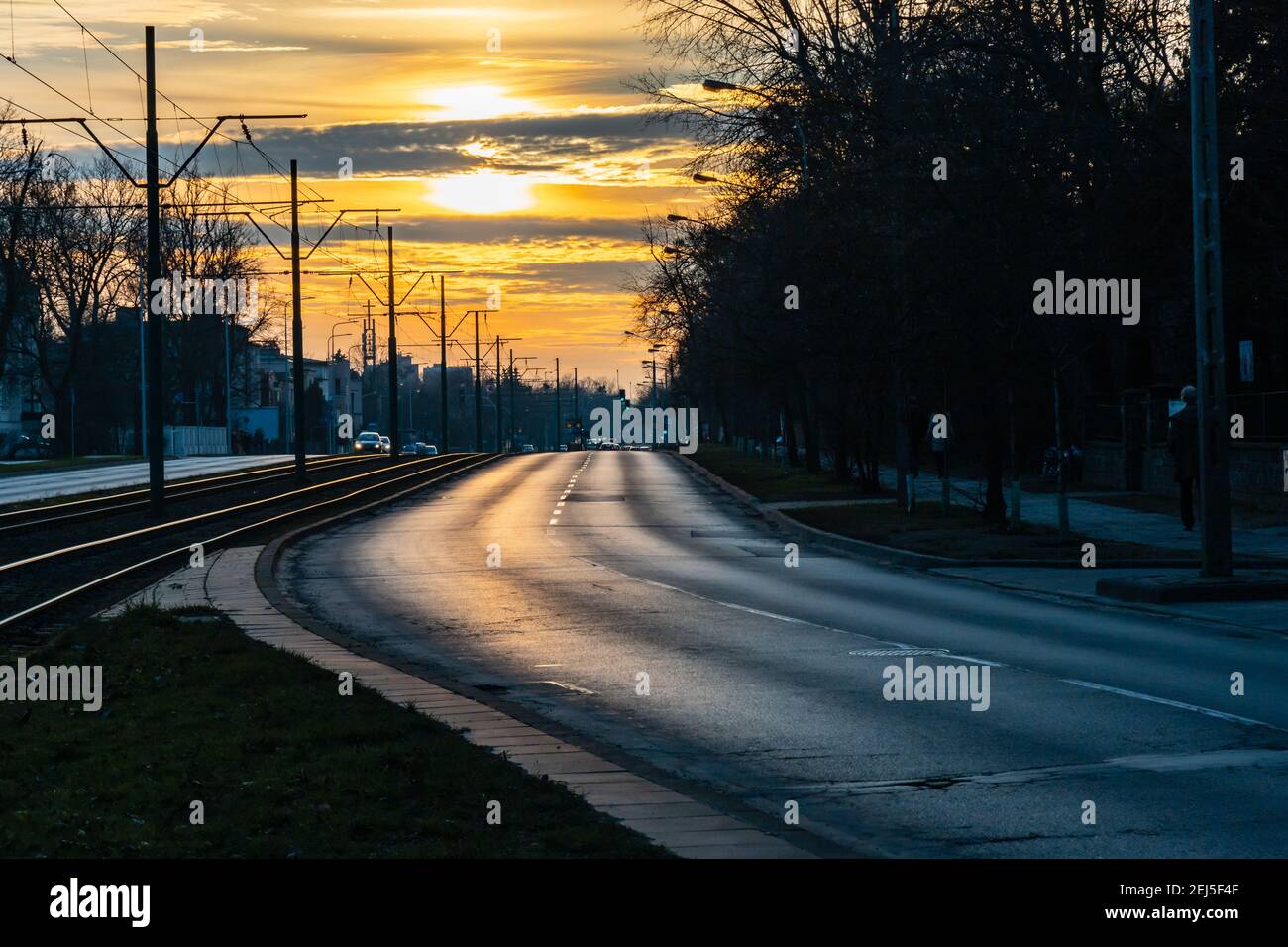 Poznan, Polonia - Febbraio 15 2020 tramonto nuvoloso su strada a due corsie con binari del tram tra Foto Stock