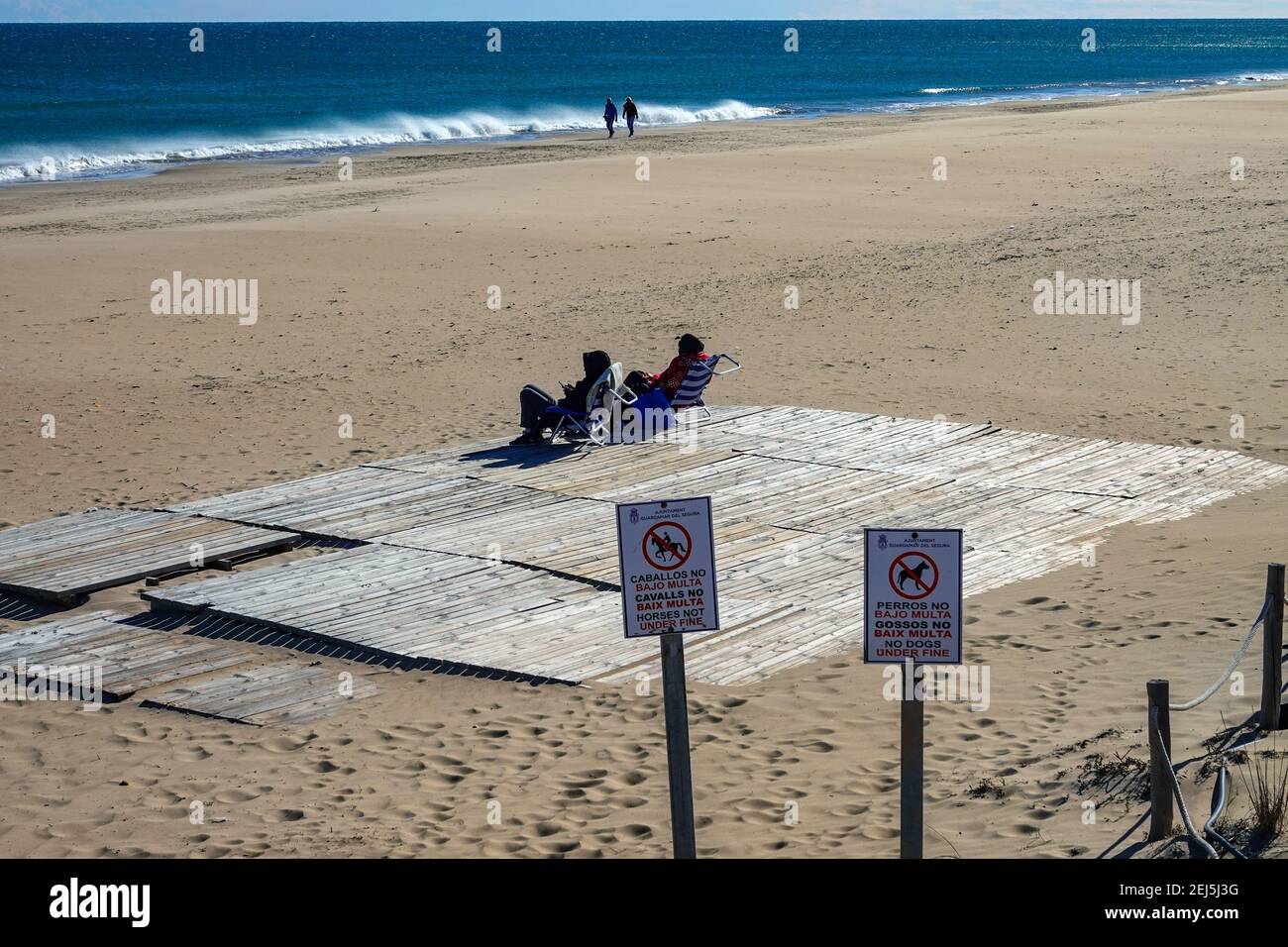Due persone sedute sul ponte sulla spiaggia, due cartelli sulla spiaggia, nessun cane, nessun cavallo, la Mata, Torrevieja, Costa Blanca, Spagna Foto Stock