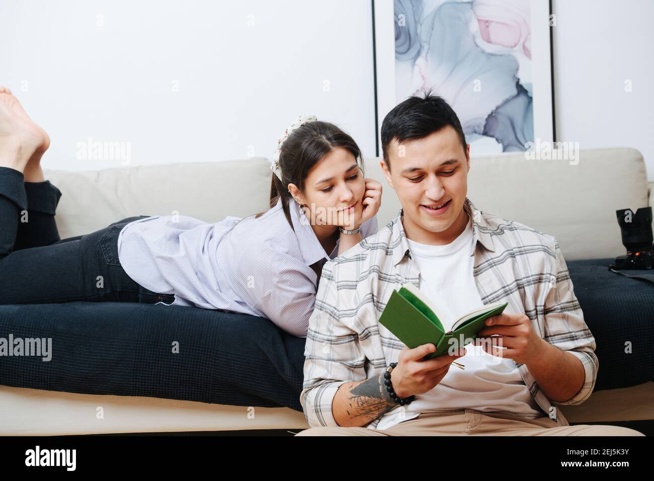 Una giovane coppia sposata, un marito legge un libro alla moglie Foto Stock