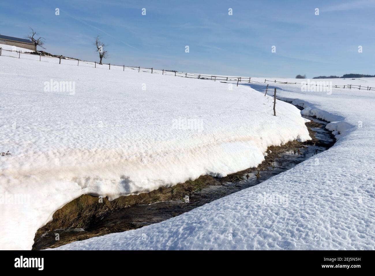Sciogliere il cielo di neve sopra il paesaggio invernale campo invernale con torrente, ruscello campo di montagna ceca Foto Stock