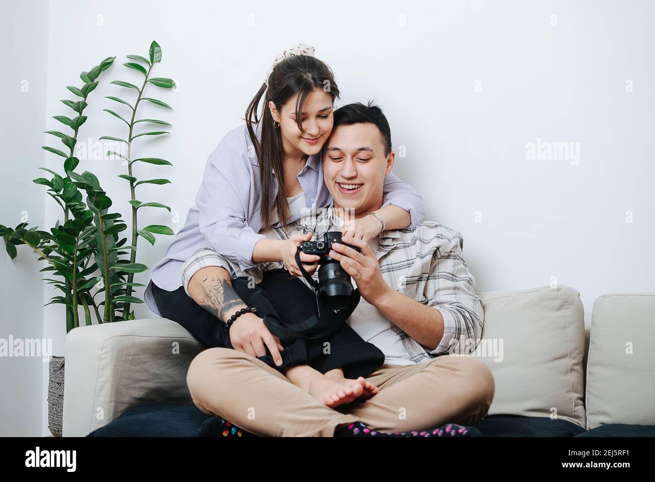 Una giovane coppia seduta su un divano che guarda le immagini dentro la fotocamera Foto Stock