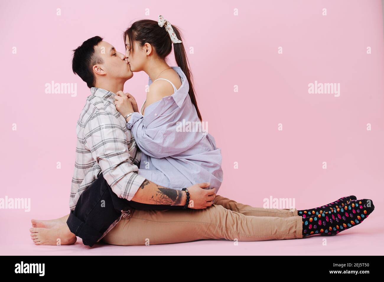 Giovane coppia abbracci e bacia su sfondo rosa Foto Stock
