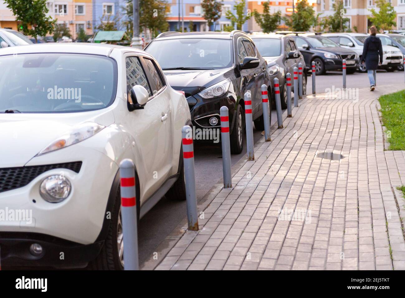 Pali per parcheggio auto. Le auto sono parcheggiate parallelamente alle case. Foto Stock