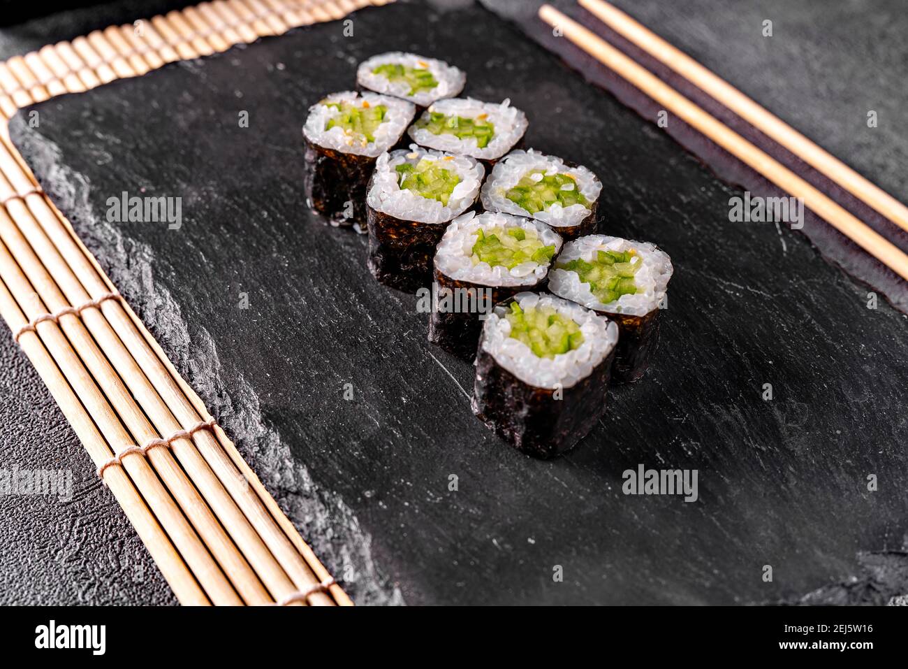 Classico rotolo Maki con cetriolo su sfondo nero a specchio Foto Stock