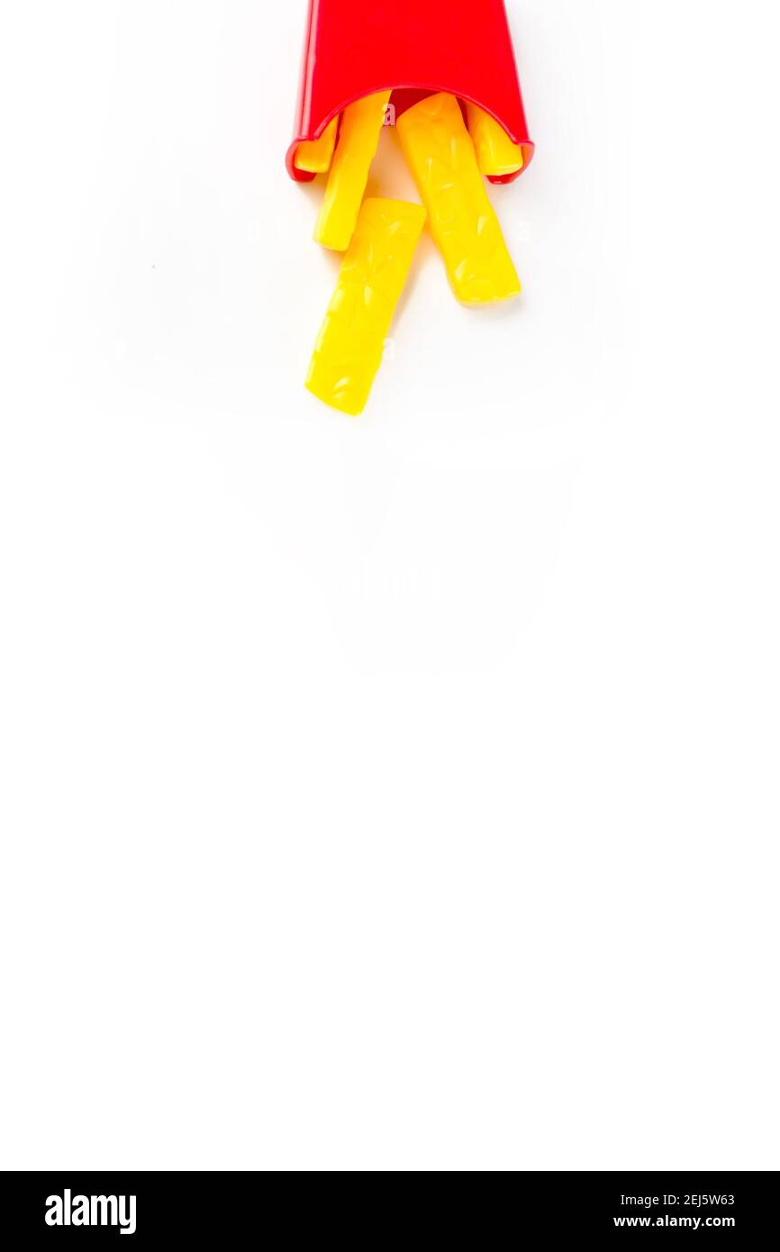 Il modello in miniatura fritto di patate cade dall'alto. Piccolo modello di patatine fritte su sfondo bianco. Concetto creativo di cibo spazzatura Foto Stock