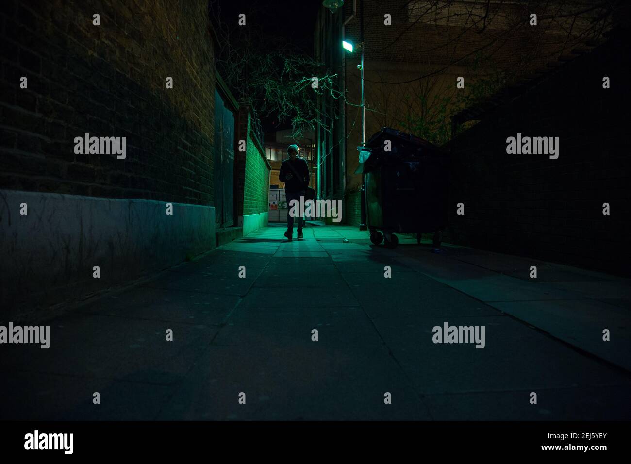 LONDRA - 28 MARZO 2015: Un uomo dalle silhouette retroilluminate cammina lungo un vicolo nel London Bridge. Foto Stock