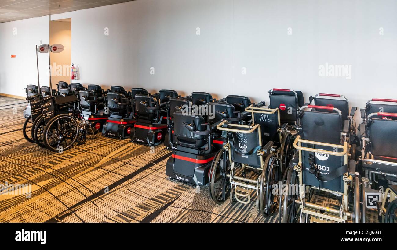 Flotta di sedie a rotelle dell'aeroporto internazionale di Singapore, parcheggiata in un terminal Foto Stock