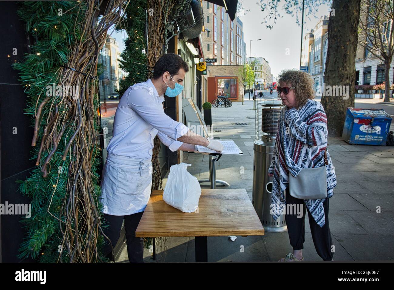 Inghilterra / Londra / UN ristorante libanese si adatta al blocco Covid-19. Il proprietario consegna un ordine a un cliente al di fuori del ristorante. Foto Stock