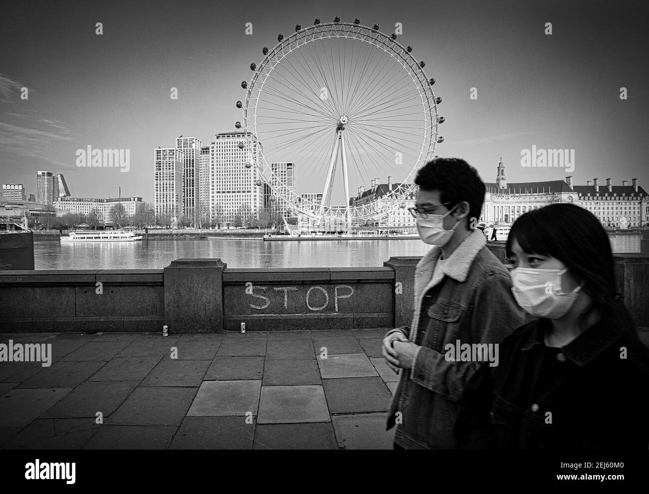 GRAN BRETAGNA / Inghilterra / Londra / Business prende un colpo come turisti shun UK .Couple indossando una maschera facciale come they camminare lungo il Tamigi argine. Foto Stock