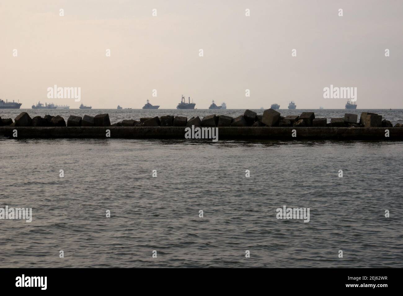 Il traffico marittimo sulla Baia di Jakarta è visto dal bacino del Porto di Jakarta, con strutture frangiflutti in primo piano. Porto di Giacarta, Tanjung Priok, Jakarta, Indonesia. Foto Stock