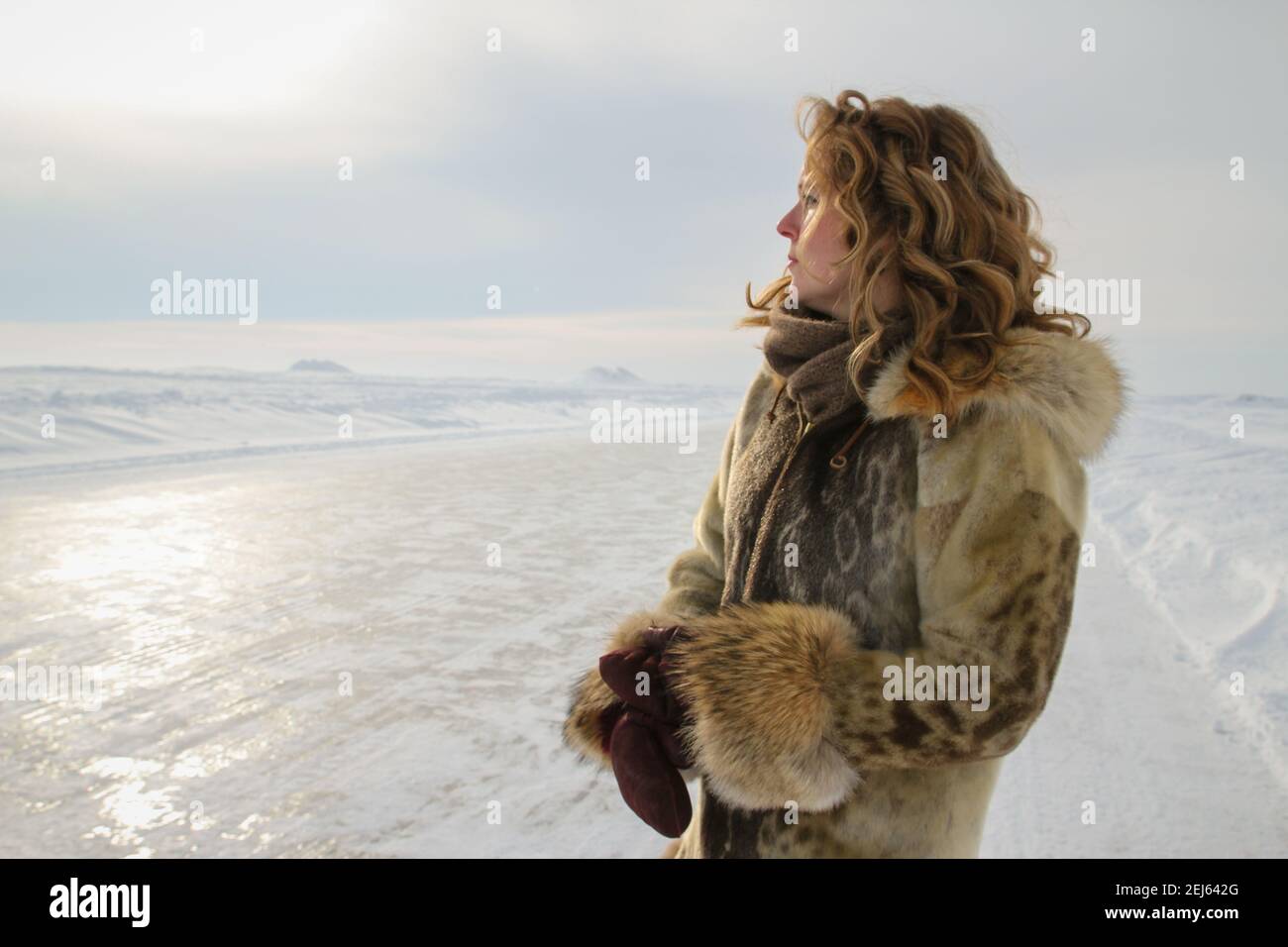 Donna caucasica nei suoi 30 anni, vestita in tradizionale pelle di foca inuit parka, in piedi sulla strada del ghiaccio dell'Oceano Artico, territori del Nord-Ovest, Canada. Foto Stock